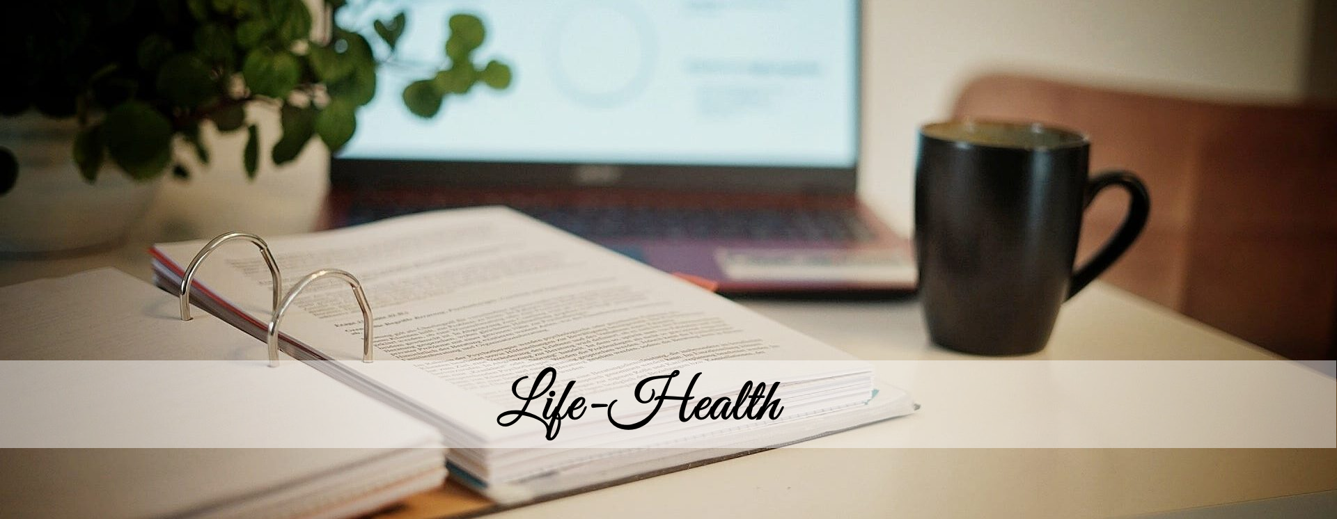 Offener Ordner mit Dokumenten auf einem Schreibtisch, daneben eine schwarze Kaffeetasse, im Hintergrund ein Laptop und eine Pflanze – in der Bildmitte der Schriftzug „Life–Health“.